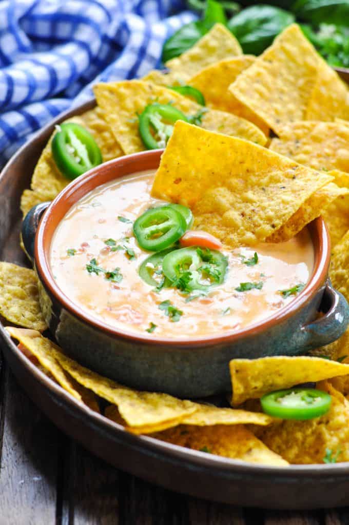 Bowl of easy queso dip with spicy jalapeno peppers and tortilla chips