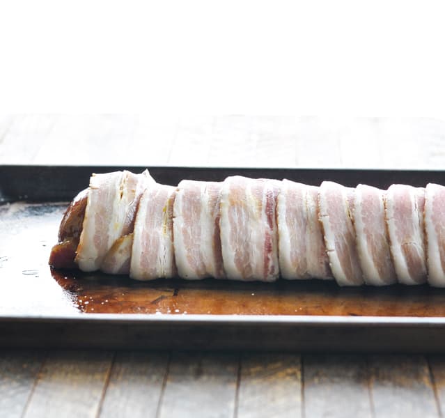Raw bacon wrapped around pork tenderloin