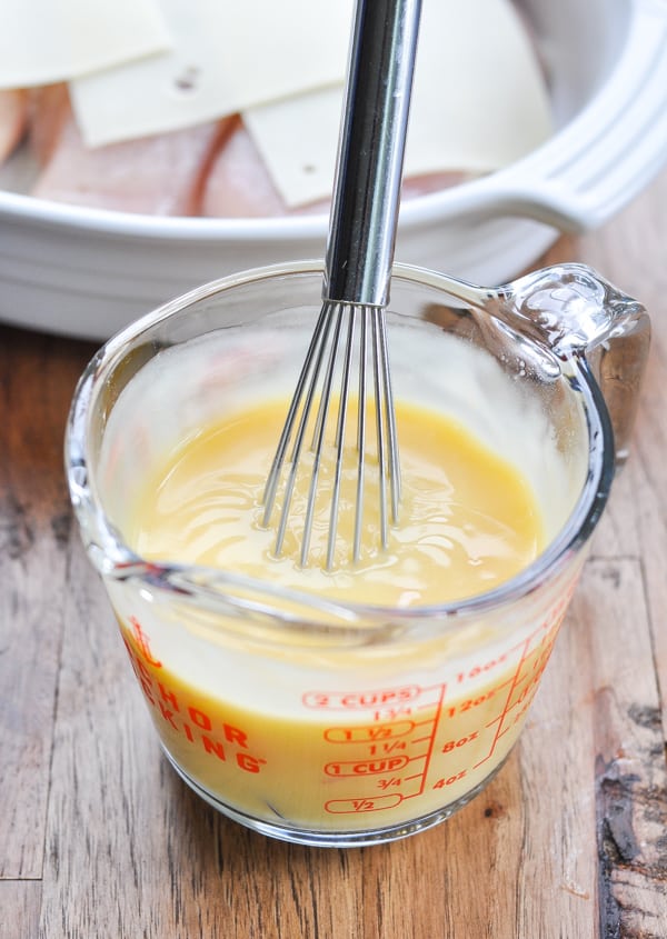 Sauce for baked chicken breasts in a glass measuring cup with whisk