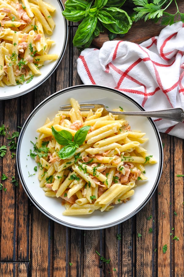 Close overhead bowl of penne with prosciutto parmesan cream sauce and a fork
