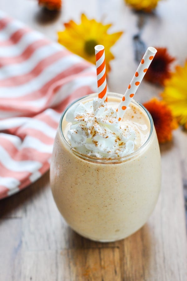 Glass of Gingerbread Pumpkin Smoothie with whipped cream and cinnamon on top