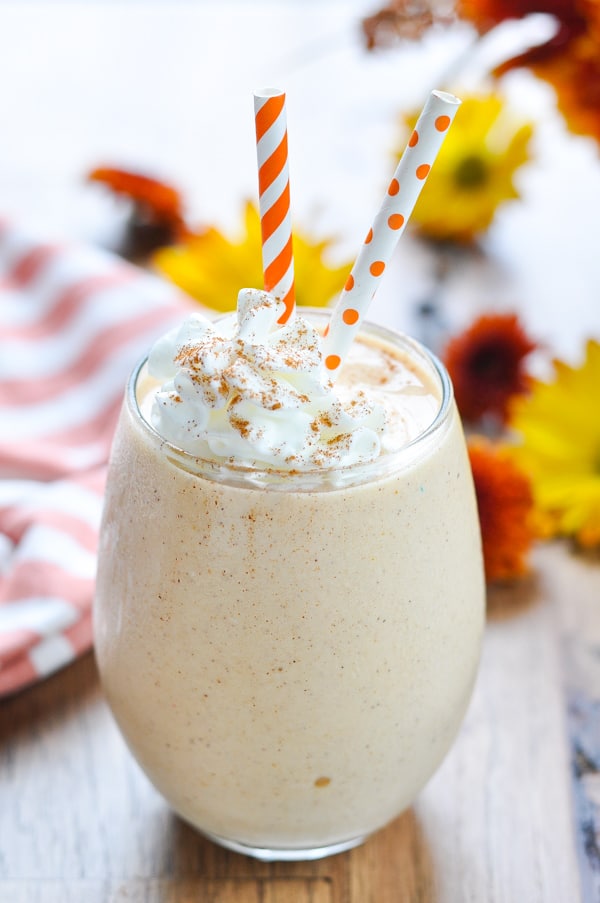 Gingerbread pumpkin smoothie with whipped cream and fall flowers in background