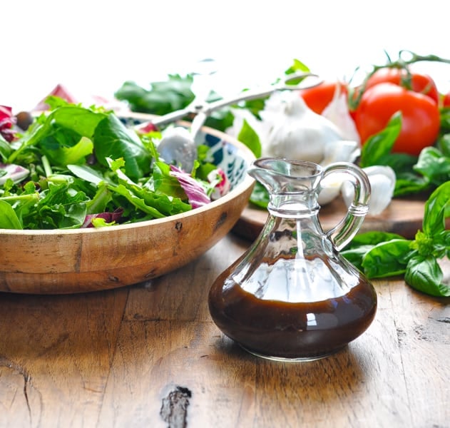 Healthy balsamic vinaigrette recipe with a bowl of mixed greens in the background