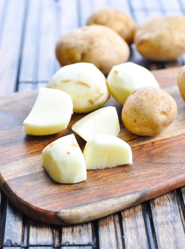 Peeled and quartered potatoes on a cutting board
