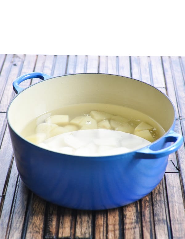 Potatoes with water in big blue pot