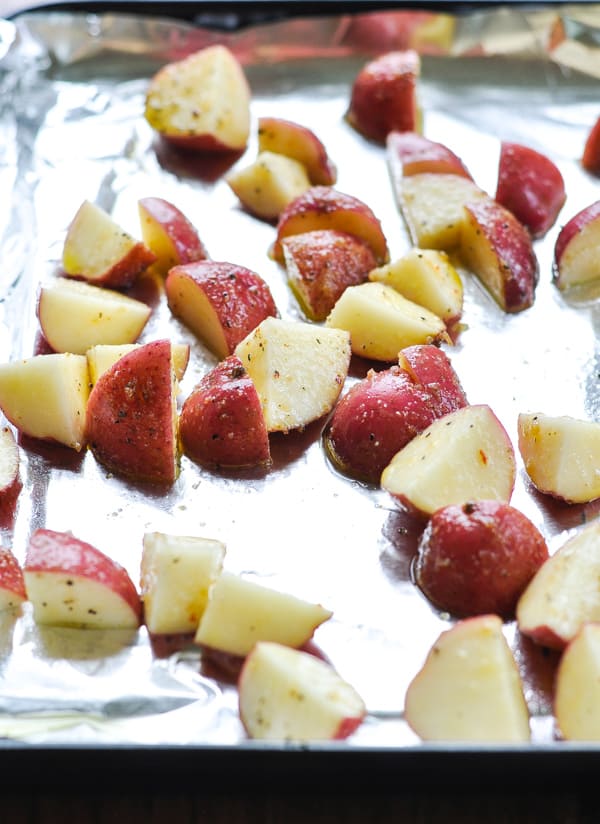 Red potatoes diced on a baking sheet and tossed with oil and seasoning