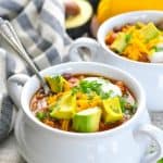 Taco soup garnished with avocado with text overlay
