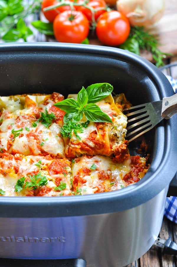 Slice of slow cooker lasagna on a spatula in the slow cooker