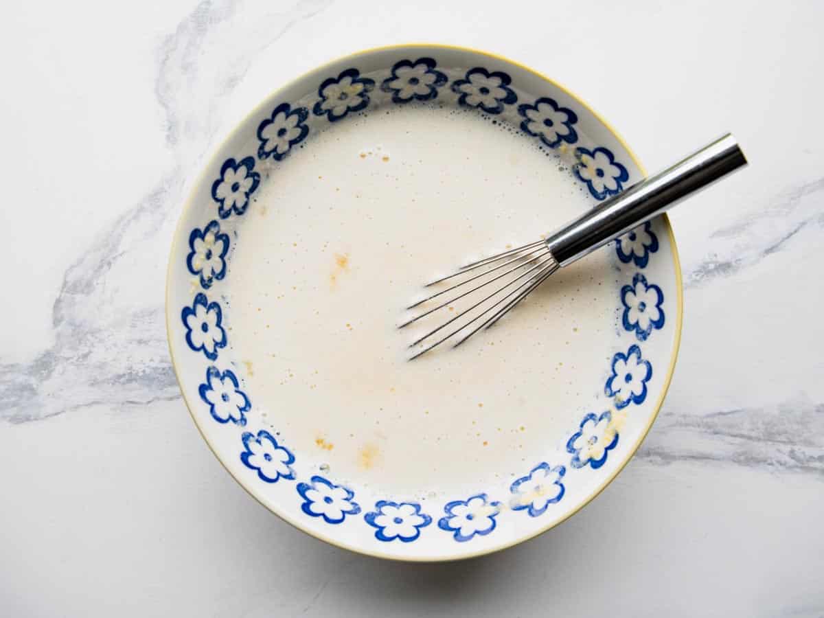 Whisking ingredients for a spoon bread recipe in a bowl.
