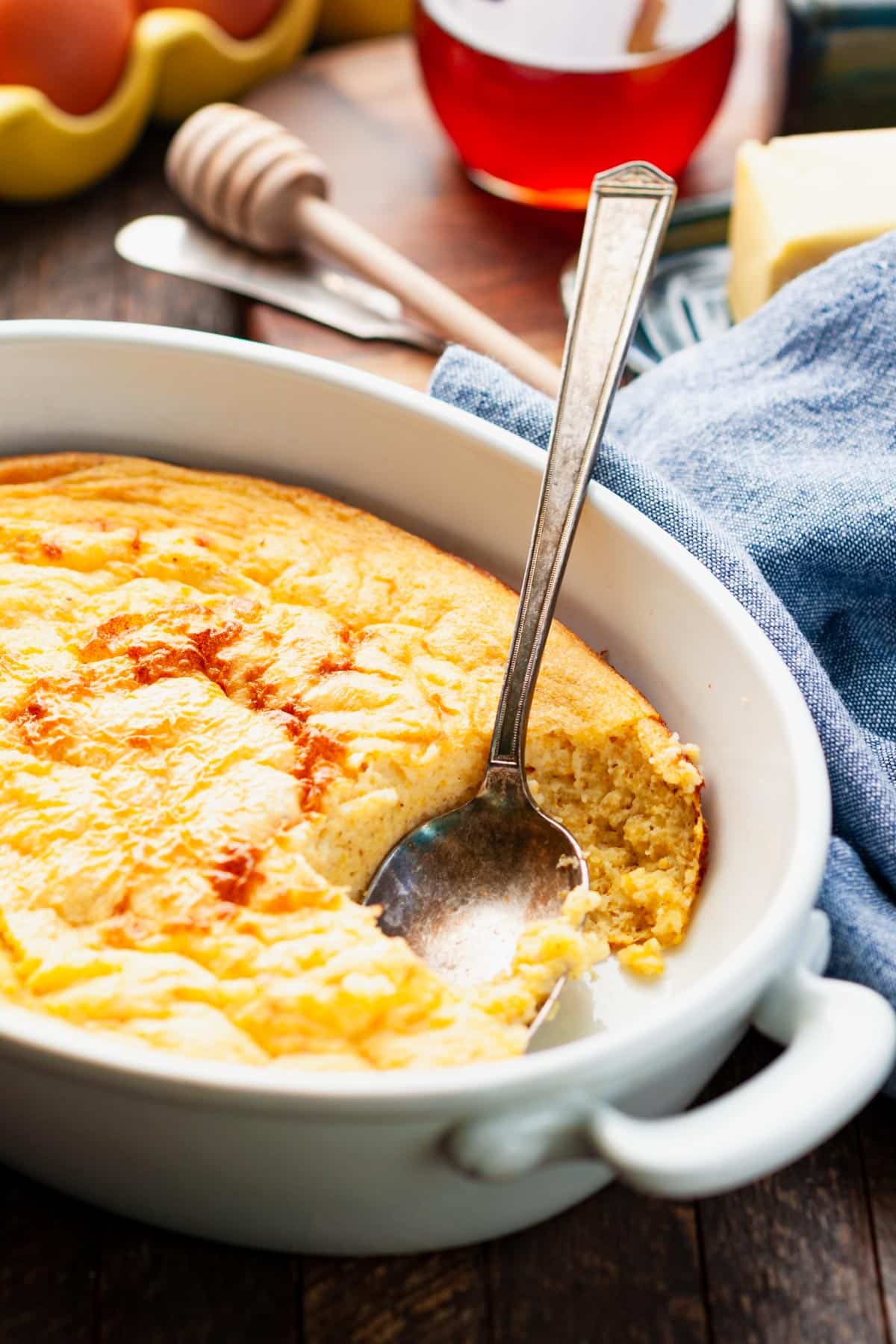 Close up side shot of a serving spoon in a pan of spoon bread.