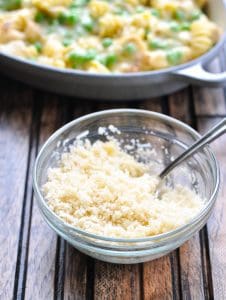 Buttered panko breadcrumbs mixed with Parmesan cheese in a glass bowl