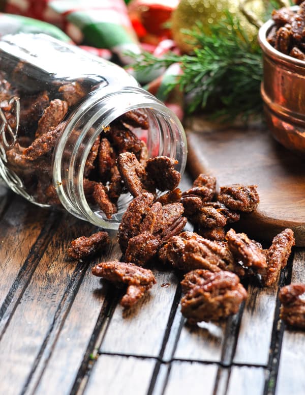 Candied pecans spilling out of a glass jar