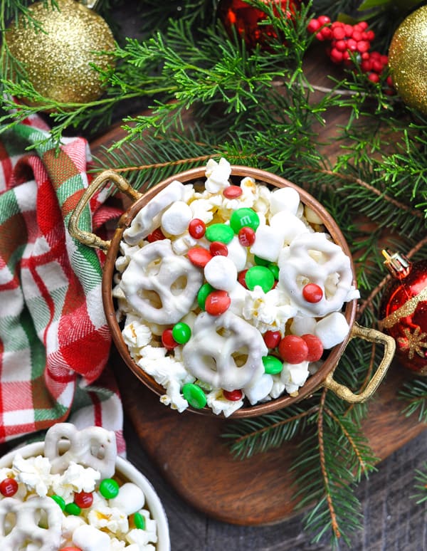 Overhead image of bowl of Christmas snack mix surrounded by decorations