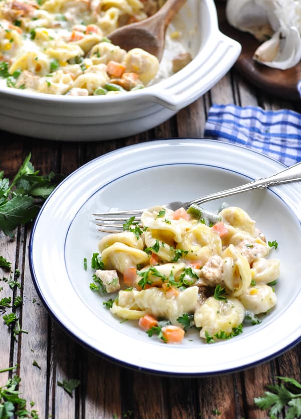 Bowl of tortellini alfredo with chicken garnished with parsley