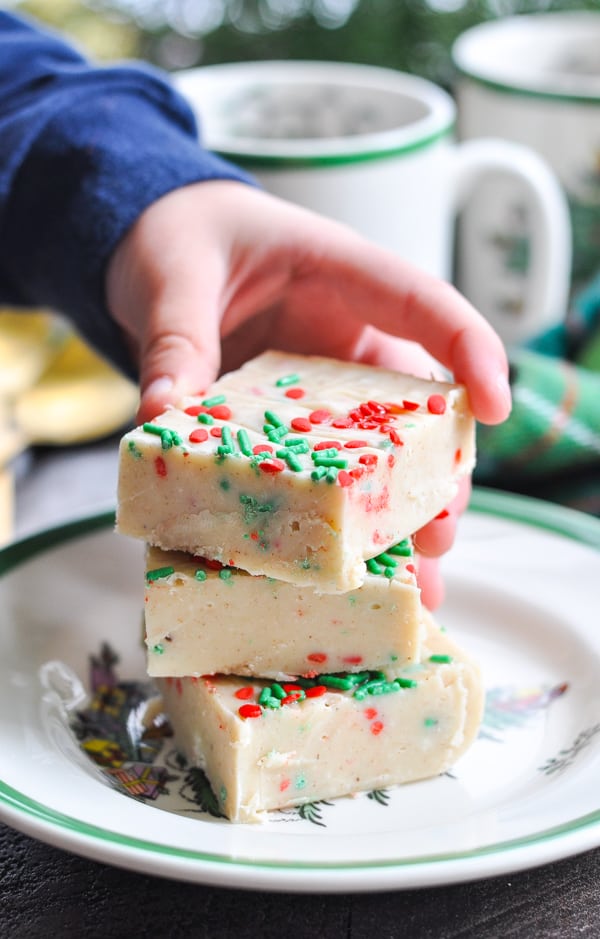 Child's hand picking up a square of microwave fudge for Christmas