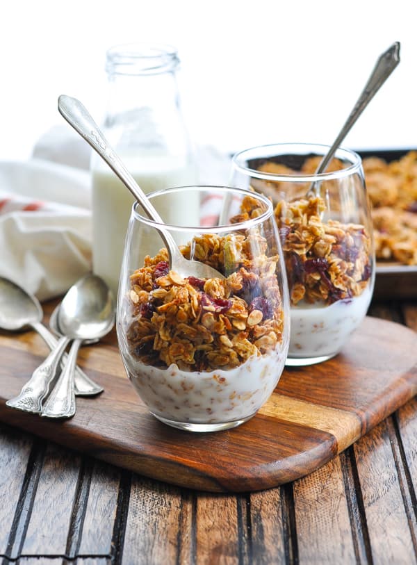Two glasses of homemade nut free granola on a wooden board
