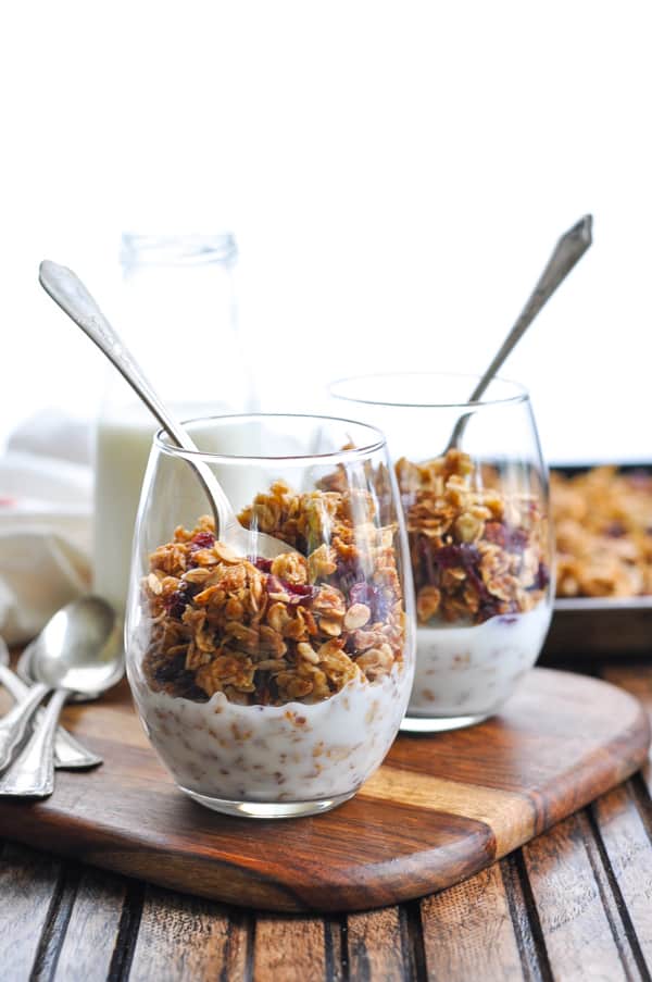 Two glasses of nut free granola recipe with milk and spoons