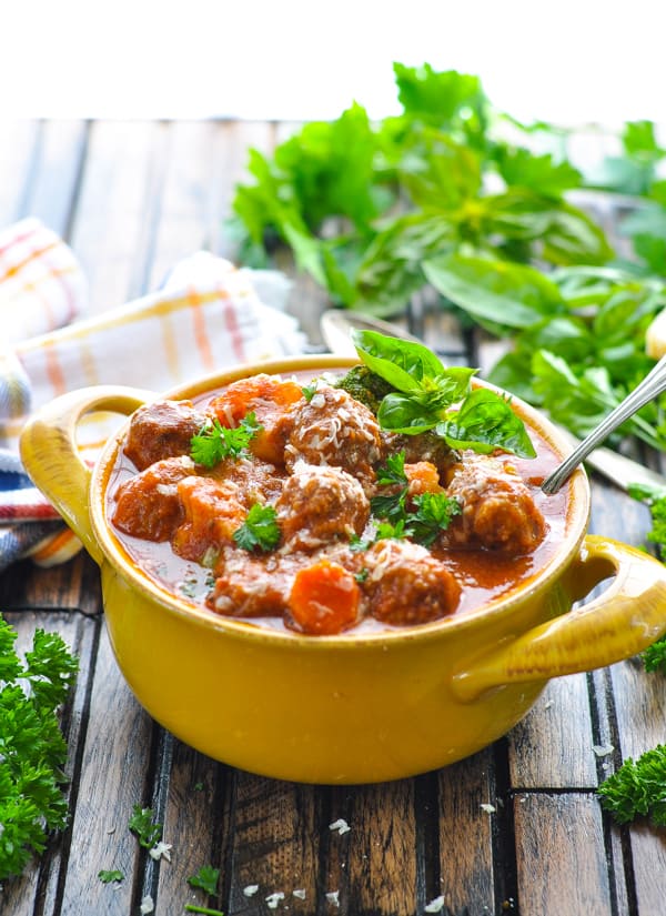 Spoon in bowl of Italian Meatball Stew garnished with fresh basil