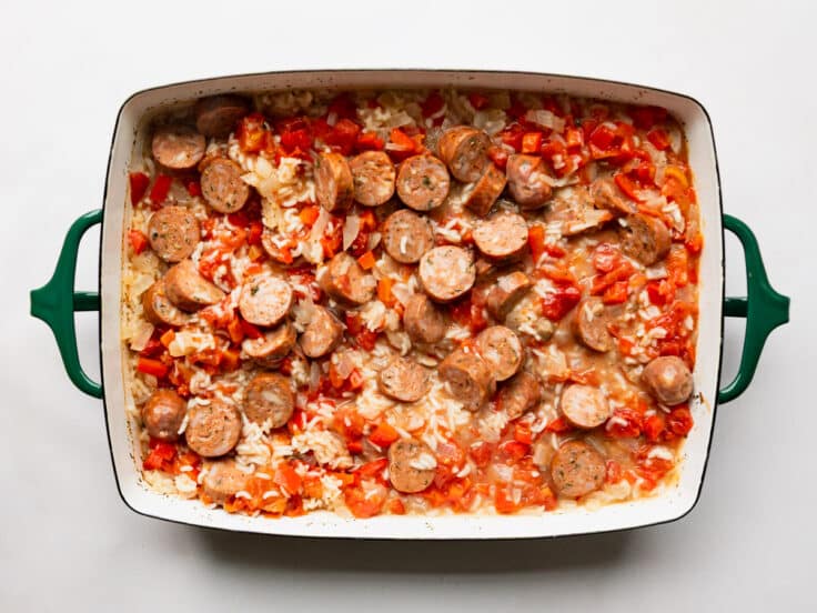 Adding sausage to the pan of rice.
