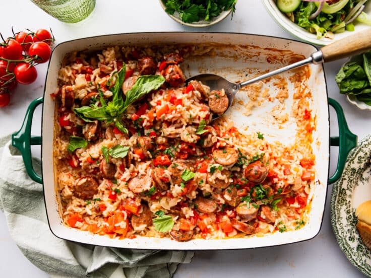 Horizontal overhead shot of a serving spoon in a pan of Italian sausage and rice casserole.
