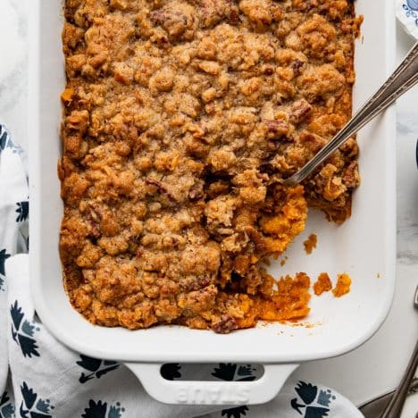 Square overhead shot of sweet potato casserole with pecans on a white table.