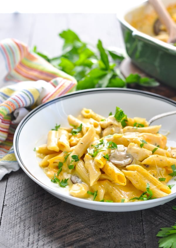 Bowl of dump and bake cheesy chicken penne pasta recipe garnished with parsley