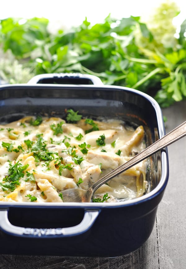 Cooked chicken and mushroom casserole in blue baking dish with serving spoon