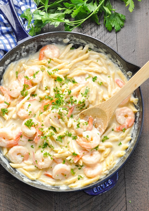 Close up image of Shrimp Alfredo in skillet with wooden spoon