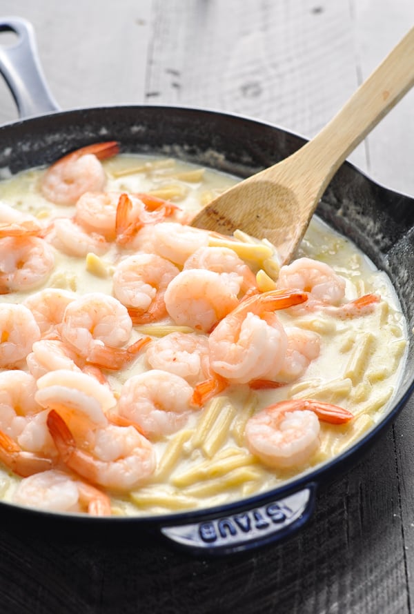 Adding shrimp to skillet with alfredo pasta