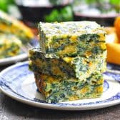 Side shot of a plate of cheesy spinach squares.