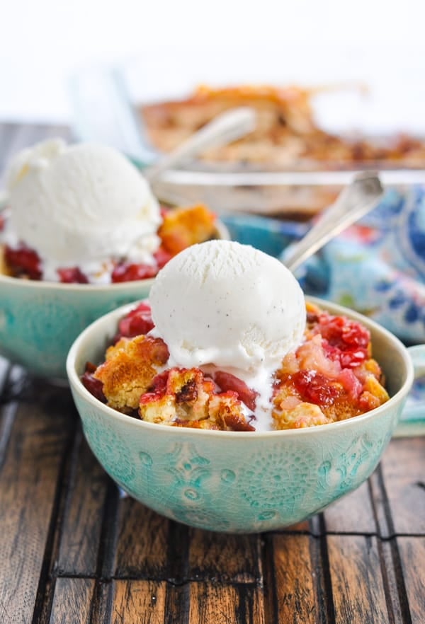 Blue bowl of cherry dump cake with scoop of ice cream on top