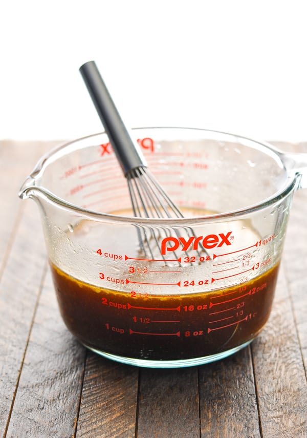 Teriyaki chicken marinade in a glass measuring cup with whisk