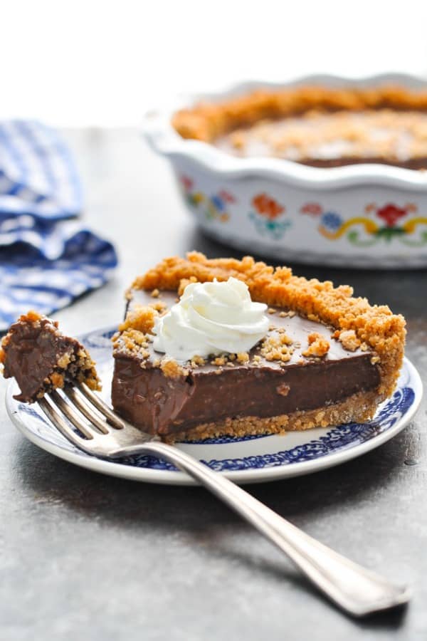 Slice of Chocolate Pudding Pie with Graham Cracker Crust on a plate with a bite taken out