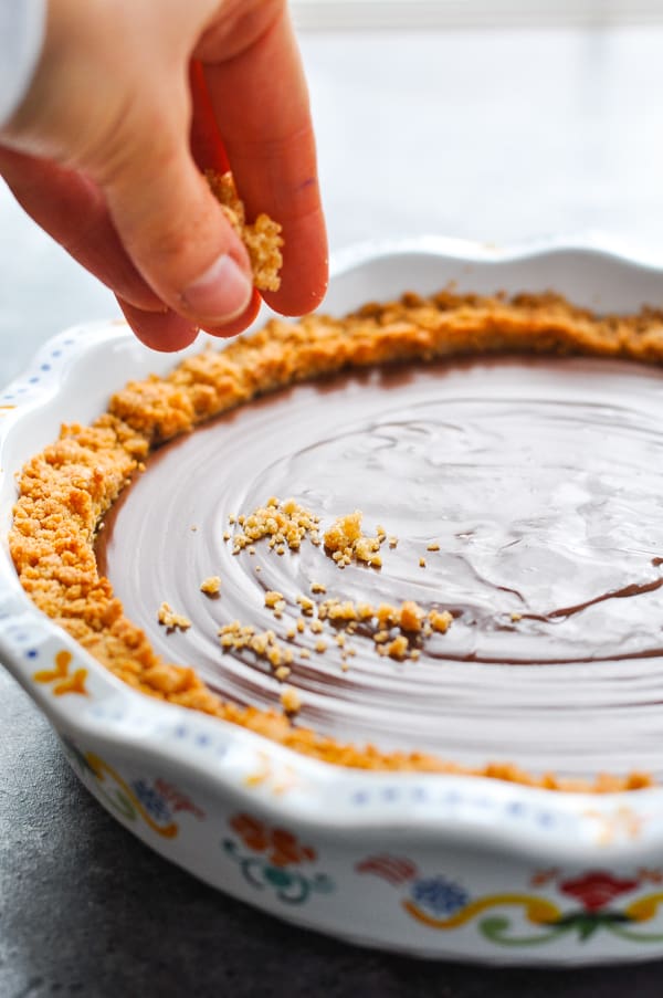 Sprinkling graham cracker crumbs on top of chocolate pudding pie
