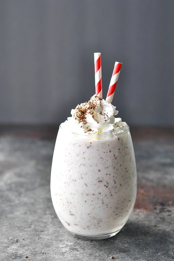 Glass of Cookies and Cream Protein Shake with two red and white striped straws