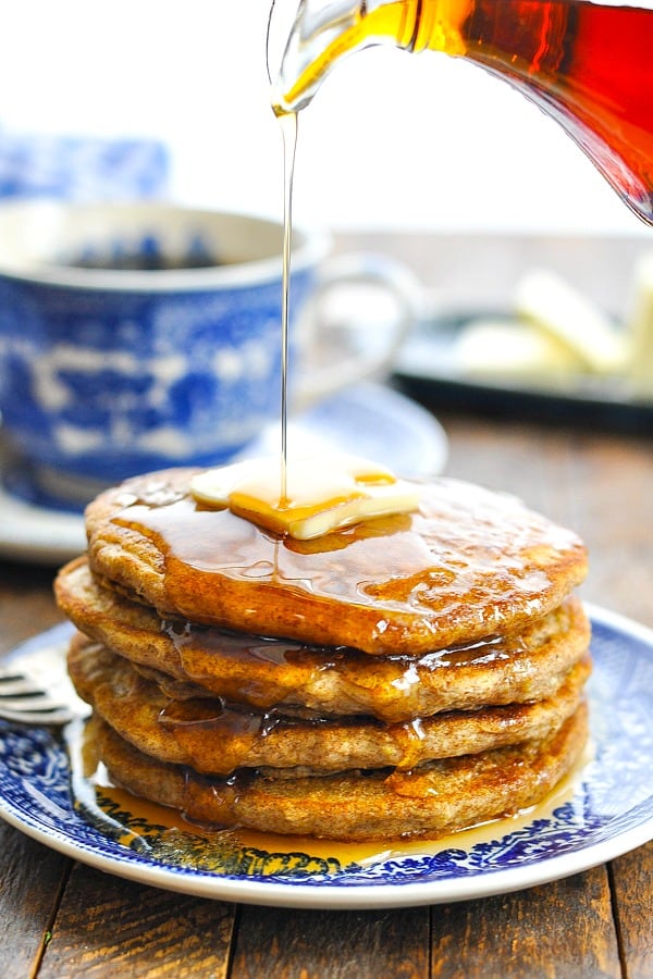 Pouring maple syrup over a stack of Oatmeal Pancakes