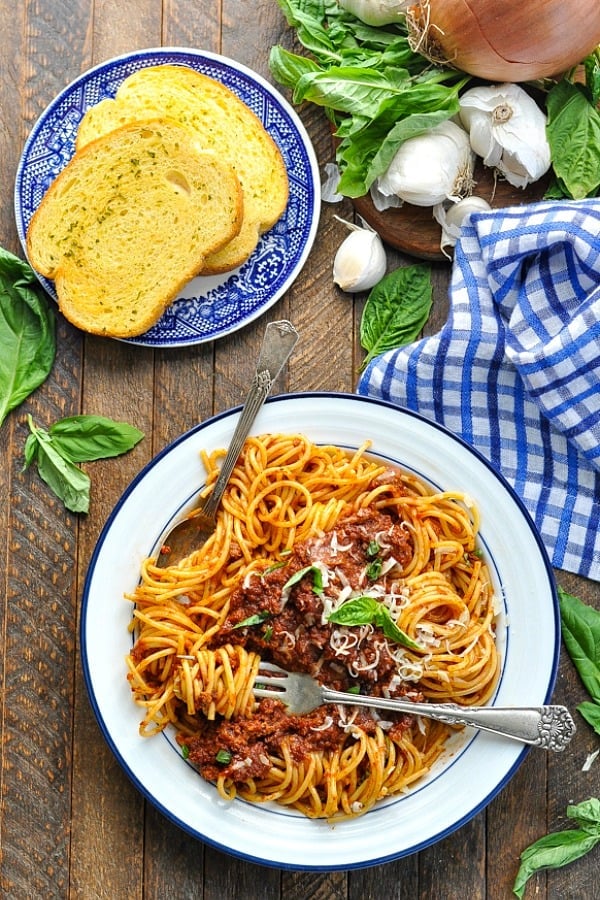 Long overhead image of spaghetti meat sauce dinner with garlic bread on the side