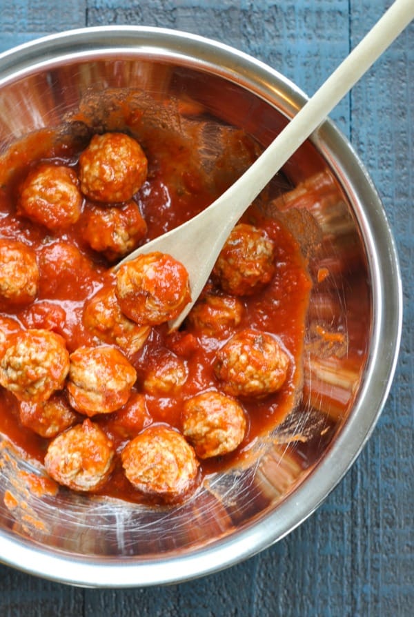 Frozen meatballs tossed with marinara sauce in a metal bowl