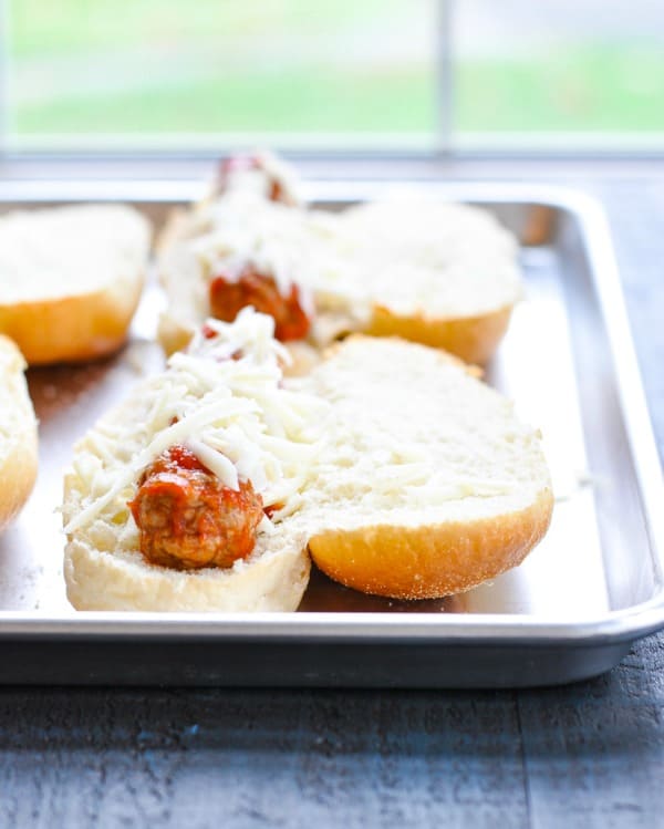 Meatball subs on a baking sheet before going in the oven