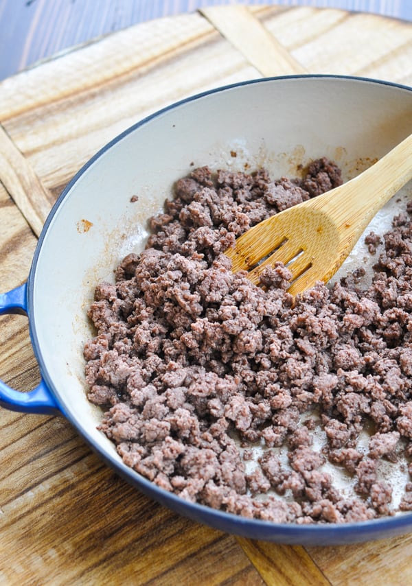 Cooked ground beef in skillet with wooden spoon
