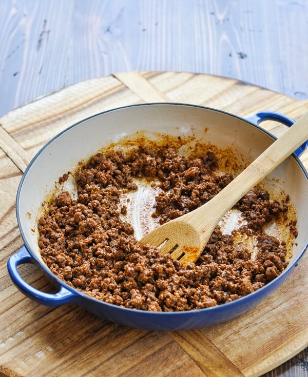 Cooked taco meat in a skillet with a wooden spoon