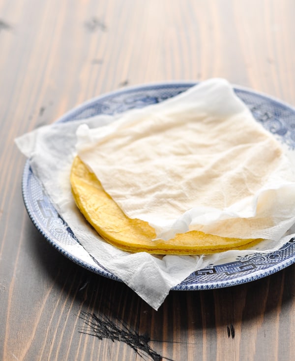 Corn tortillas on a plate wrapped in damp paper towels