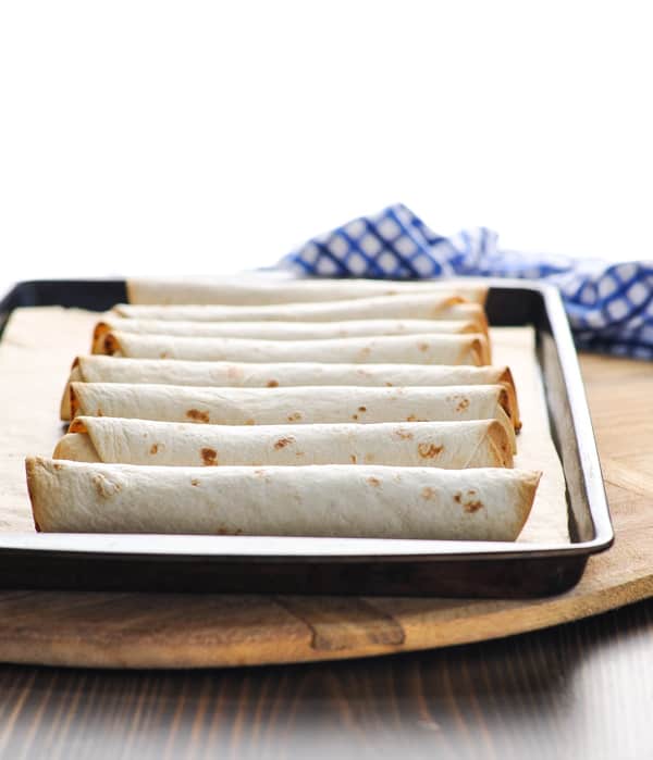 Homemade baked taquitos recipe on a baking sheet fresh from the oven