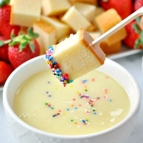 Dipping pound cake cube in a bowl of champagne white chocolate fondue