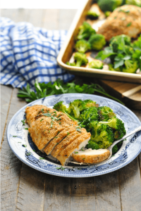 Front view of sliced garlic parmesan chicken with broccoli on a plate