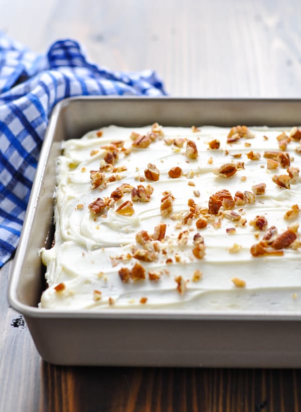 Frosted hummingbird cake in a baking dish with pecans on top