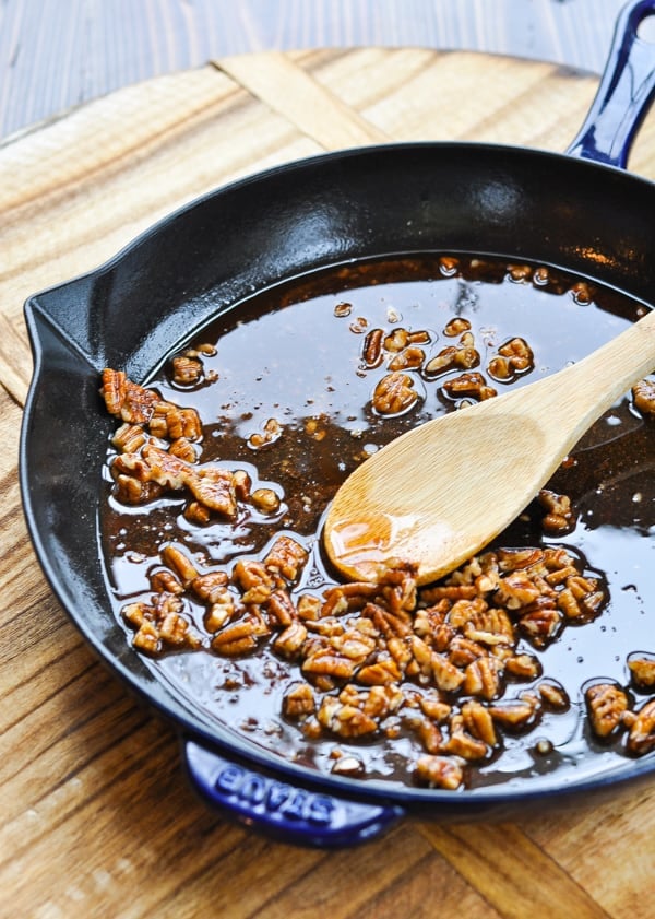 Pecans coconut oil and maple syrup in cast iron skillet