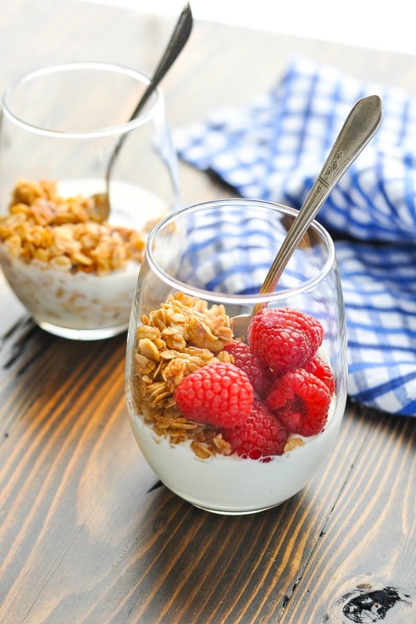 Glasses of stovetop cinnamon granola with milk yogurt and berries