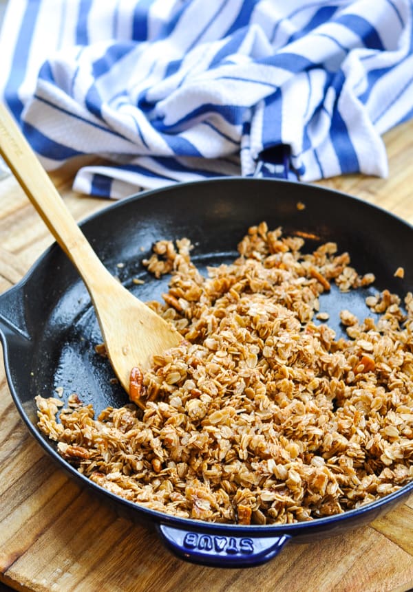 Wooden spoon in a cast iron skillet with crunchy vegan granola recipe