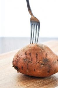 Pricking a sweet potato with a fork